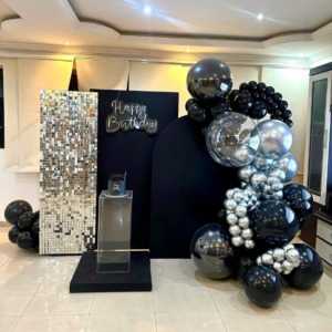 Premium black and silver birthday decoration with shimmer panel backdrop, balloon garland, Happy Birthday neon light and elegant pedestal cake stand