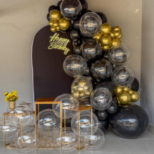 Luxury black and gold birthday decoration with matte black backdrop, bubble balloons, chrome gold balloons and Happy Birthday neon light