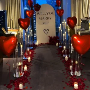Luxury marriage proposal setup with will you marry me backdrop, candle pathway and red heart balloons