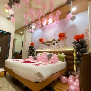 Birthday room decoration with pink and black balloons, happy birthday banner and rose petal bed decor