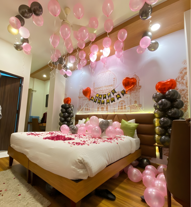 Birthday room decoration with pink and black balloons, happy birthday banner and rose petal bed decor