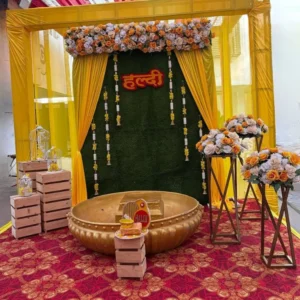 Luxury Haldi decoration with yellow drapes, floral backdrop and golden haldi tub setup