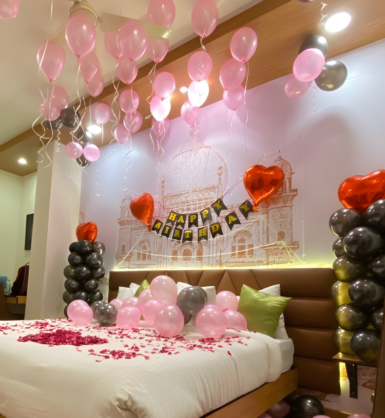 Birthday room decoration with pink and black balloons, happy birthday banner and rose petal bed decor
