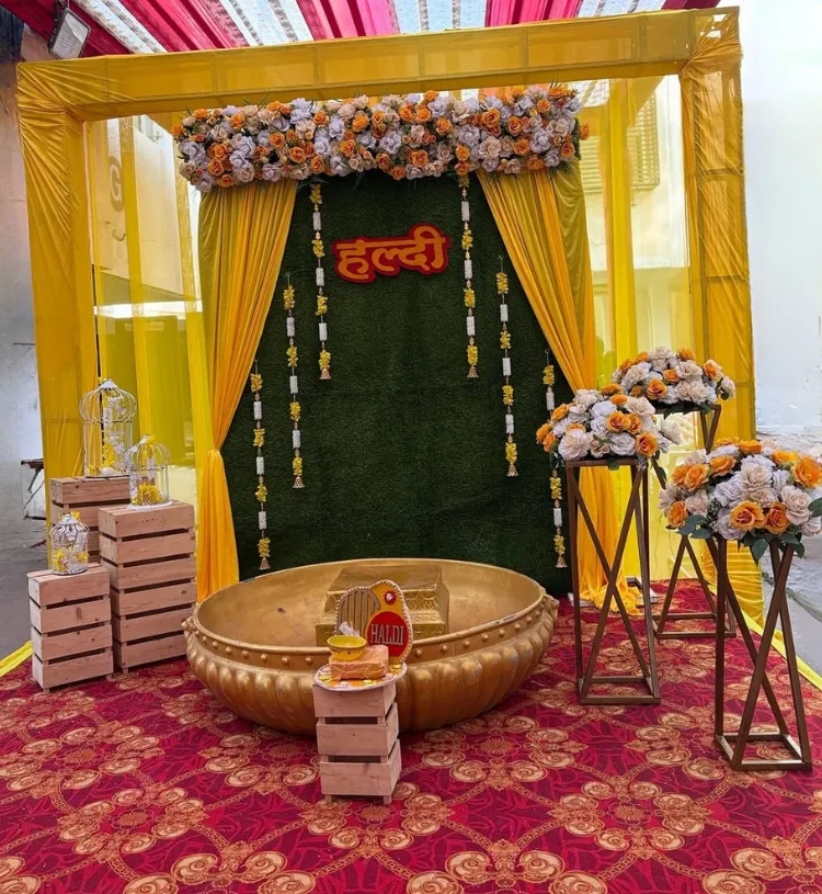 Luxury Haldi decoration with yellow drapes, floral backdrop and golden haldi tub setup