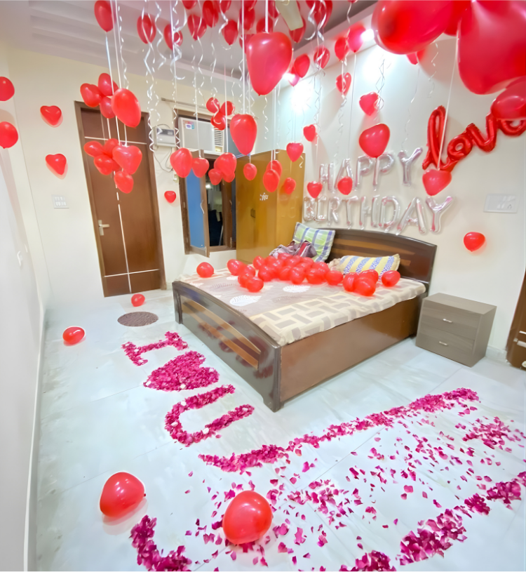 Romantic room decoration with red heart balloons, happy birthday foil letters and I Love You rose petal decoration