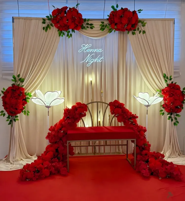 Luxury Henna Night Stage Decoration with Cream Drapes, Red Flowers and Neon Sign