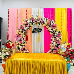 Luxury Haldi Ceremony Stage Decoration with Floral Ring Backdrop and Colorful Drapes