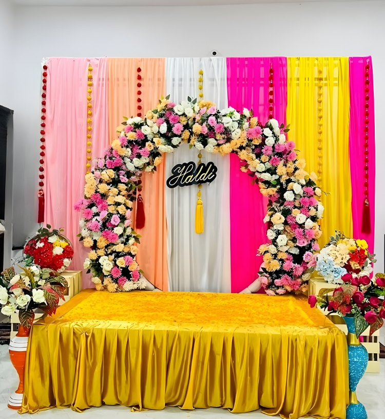 Luxury Haldi Ceremony Stage Decoration with Floral Ring Backdrop and Colorful Drapes