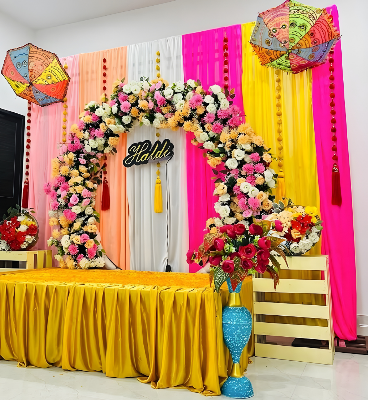 Luxury Haldi Ceremony Stage Decoration with Floral Ring Backdrop and Colorful Drapes