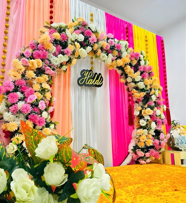 Luxury Haldi Ceremony Stage Decoration with Floral Ring Backdrop and Colorful Drapes