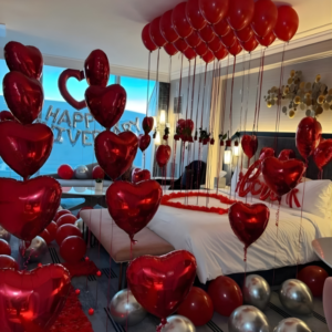 Romantic anniversary room decoration with heart balloons, rose petals and Happy Anniversary backdrop